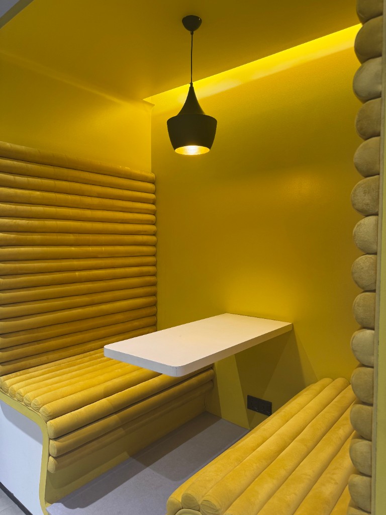Yellow glass huddle booth in an open office